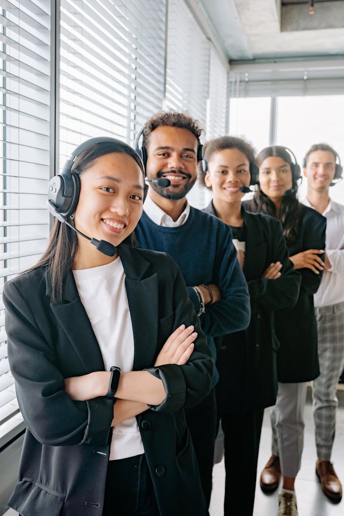 services-03 A diverse group of call center agents smiling and standing in line with headsets in an office.